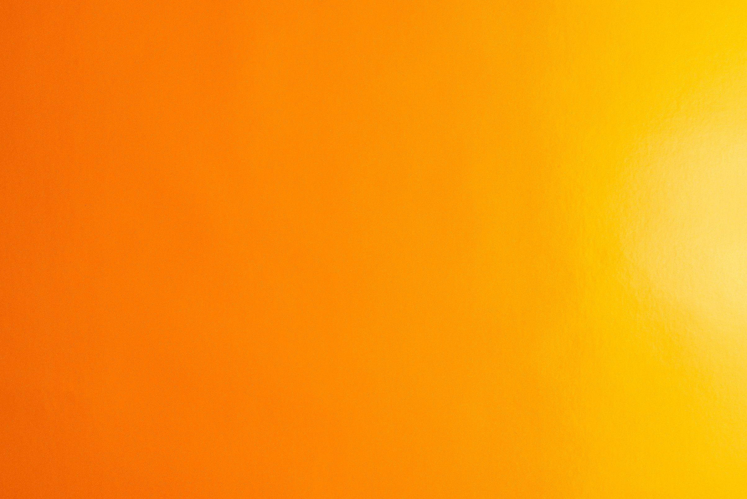 Orange background made of real colored paper, illuminated by a soft light from the right.